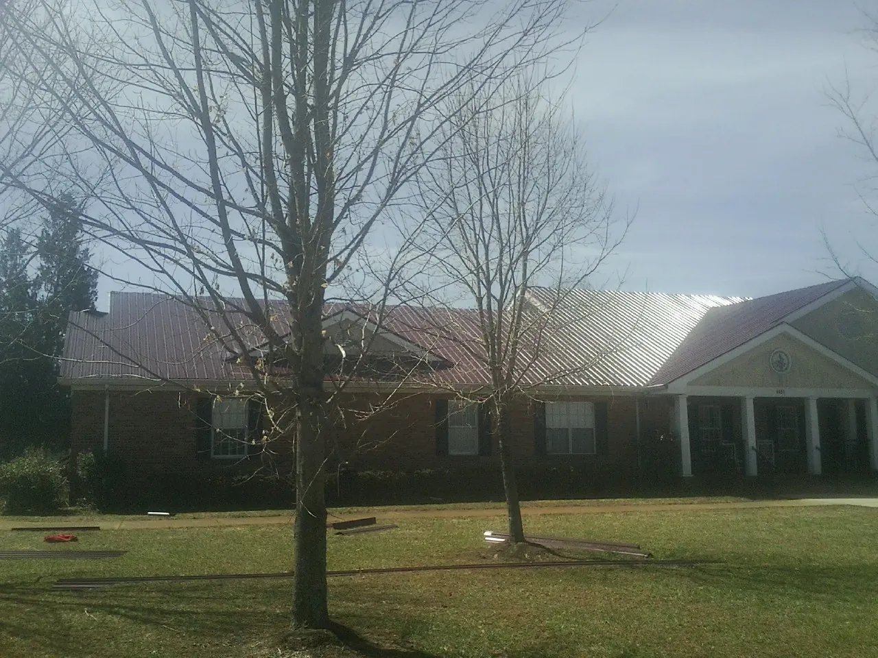 Red metal roof on a brick building seen from the front lawn in Western
