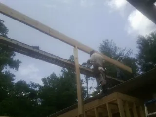 Carpenter setting a ridge beam over a new addition frame — Ice Dam Removal by Roofing Brothers in Western
