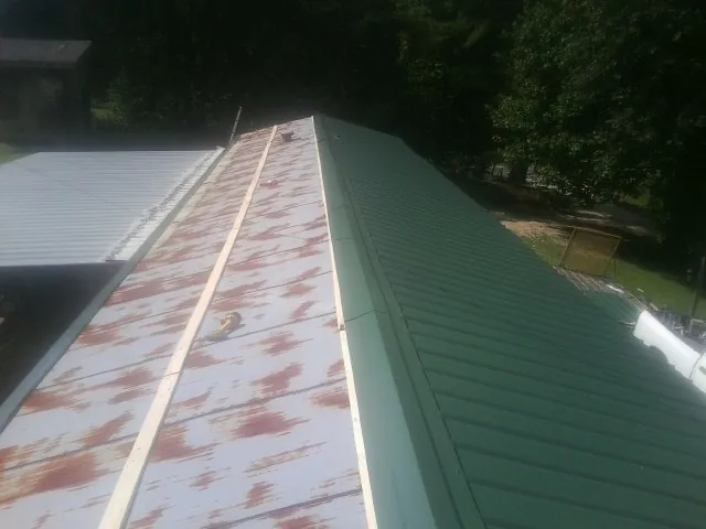 Old rusted panels beside newly installed green metal roofing — Wind Damage Roof Repair by Roofing Brothers in Western