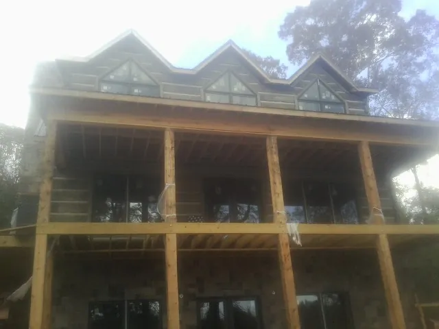 Dormers and porch framing on a large log home under construction — Roof Coating work by our crew in Western