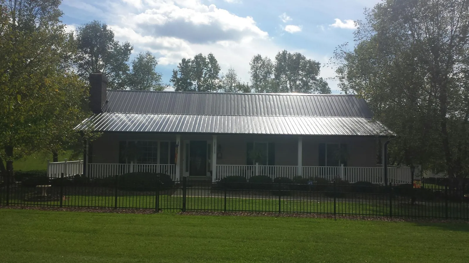 Gray metal roof on a brick ranch with a full width front porch — Gutter Guard Installation work by our crew in Western